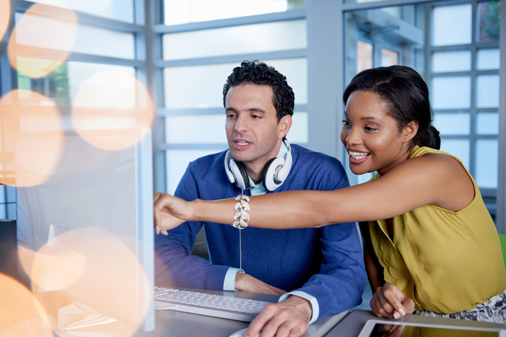 Two  colleages discussing ideas using a tablet and computer